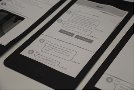 Close-up photo of a paper prototype mobile phone screen displaying a fictional text message conversation.